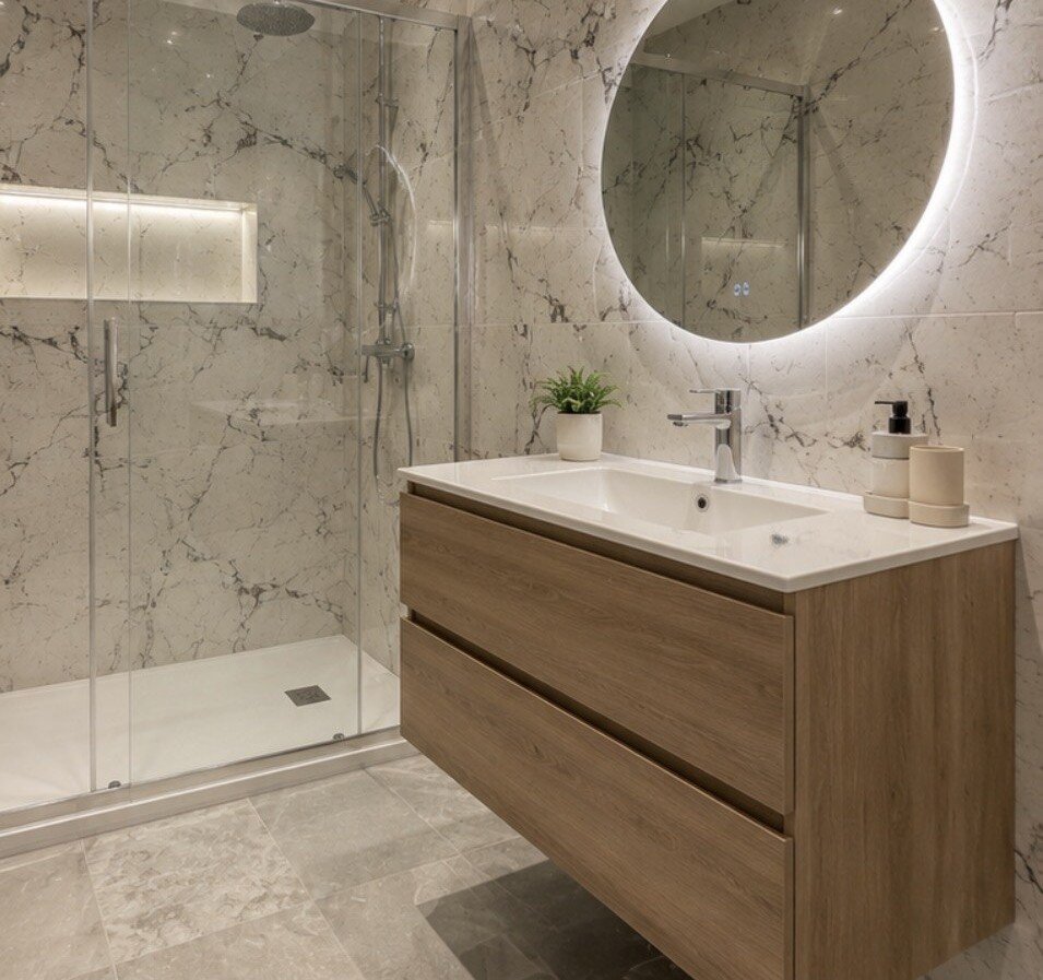 Salle de bain après rénovation : douche à l'italienne en marbre, meuble vasque bois, miroir lumineux