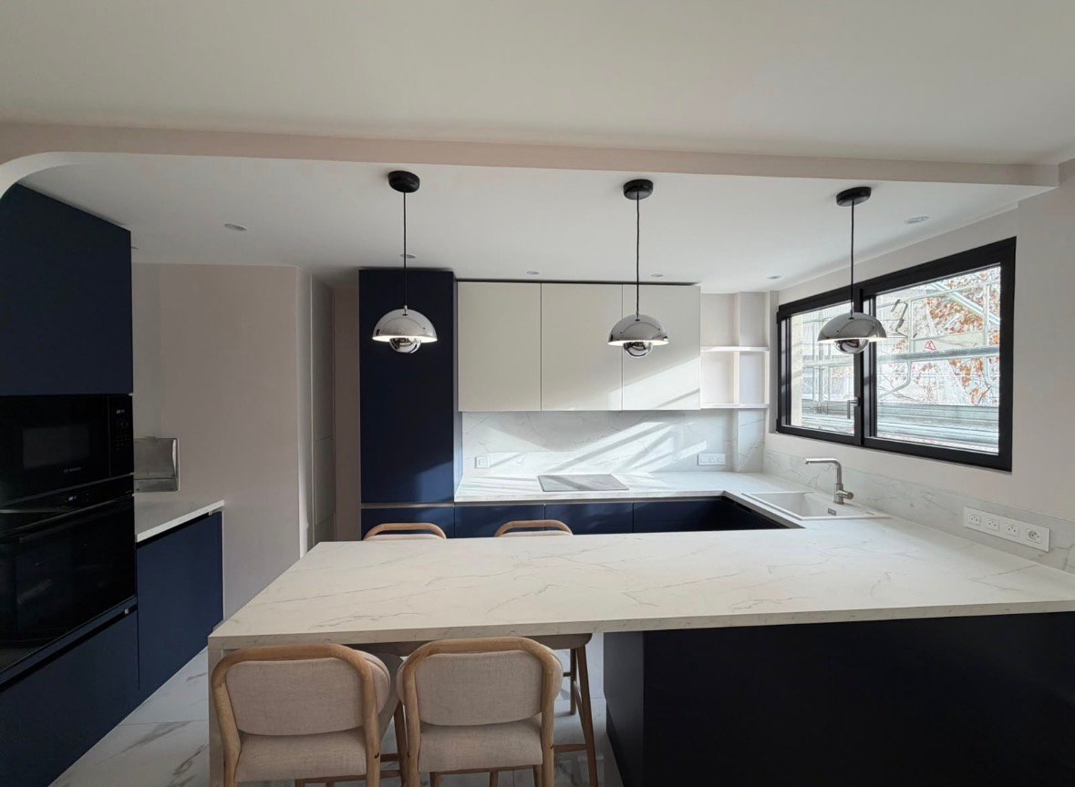 Cuisine du projet Paris 12 : meubles bleu nuit, plan de travail en marbre et suspensions boules chromées