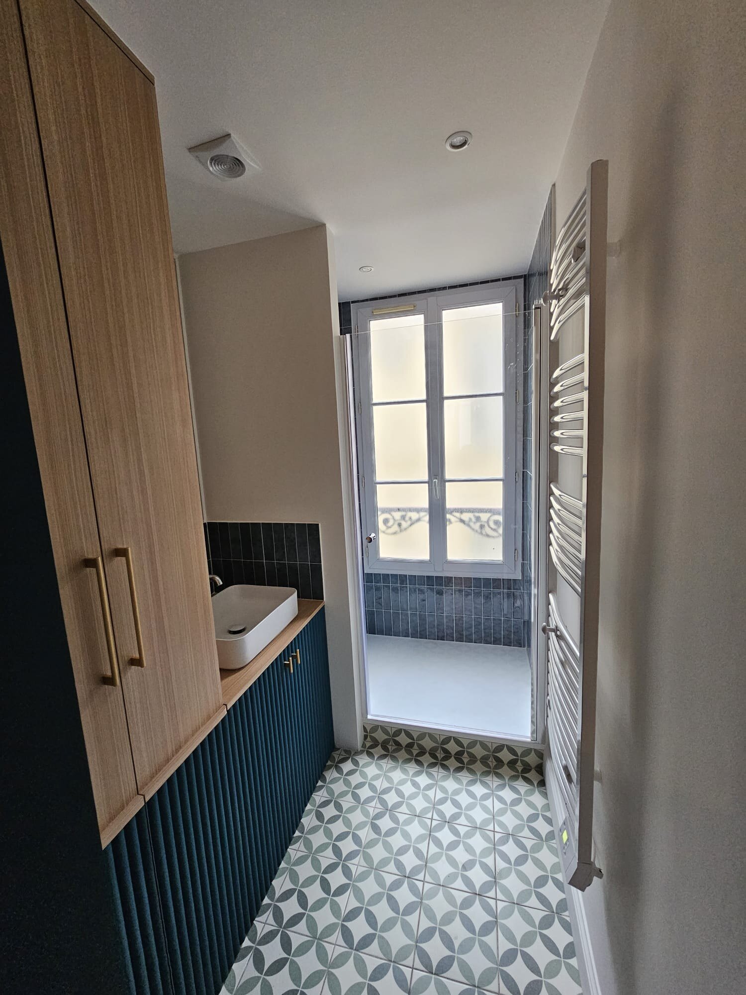 Salle de bain avec meuble bois cannelé bleu et sèche-serviette chromé