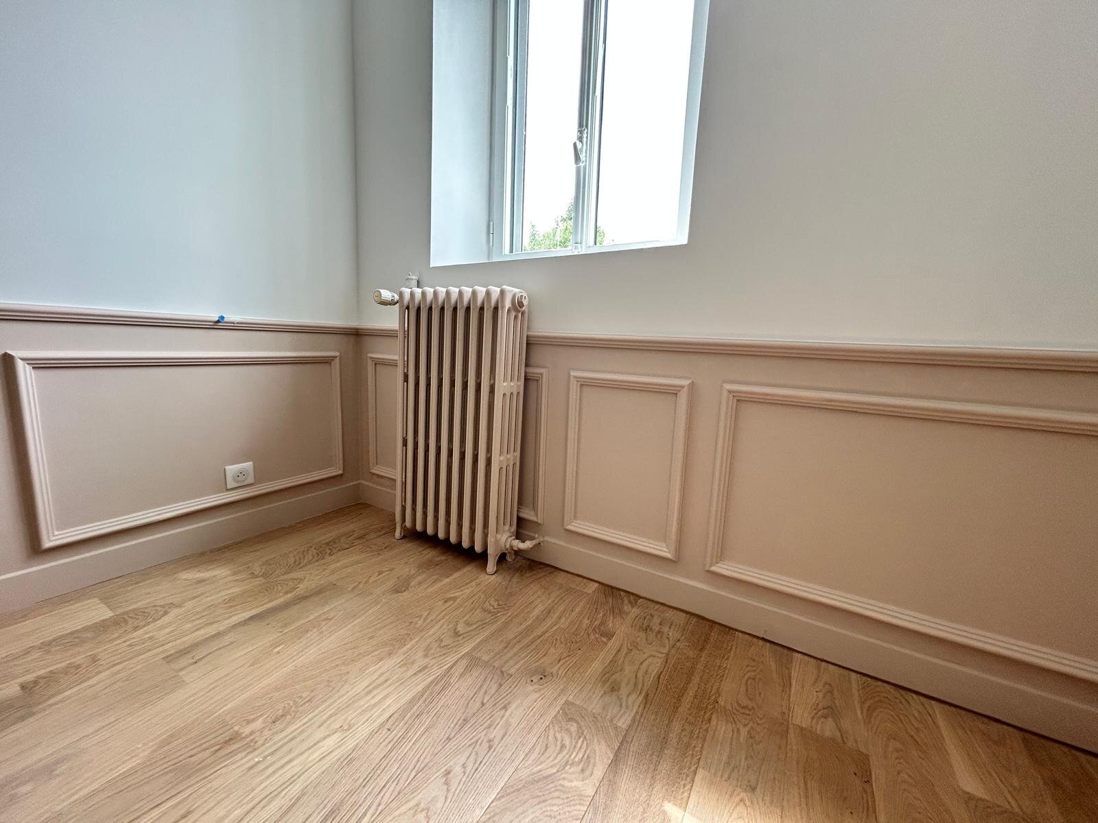 Chambre avec cimaises roses et radiateur en fonte