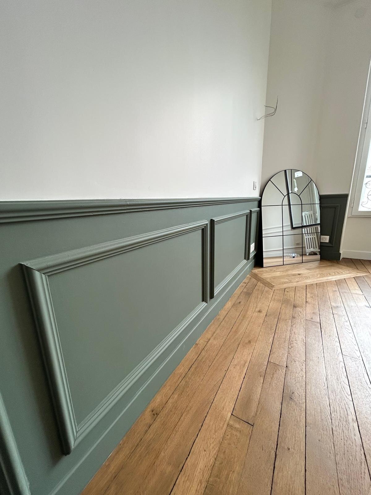 Pièce avec cimaises vert de gris et miroir arqué