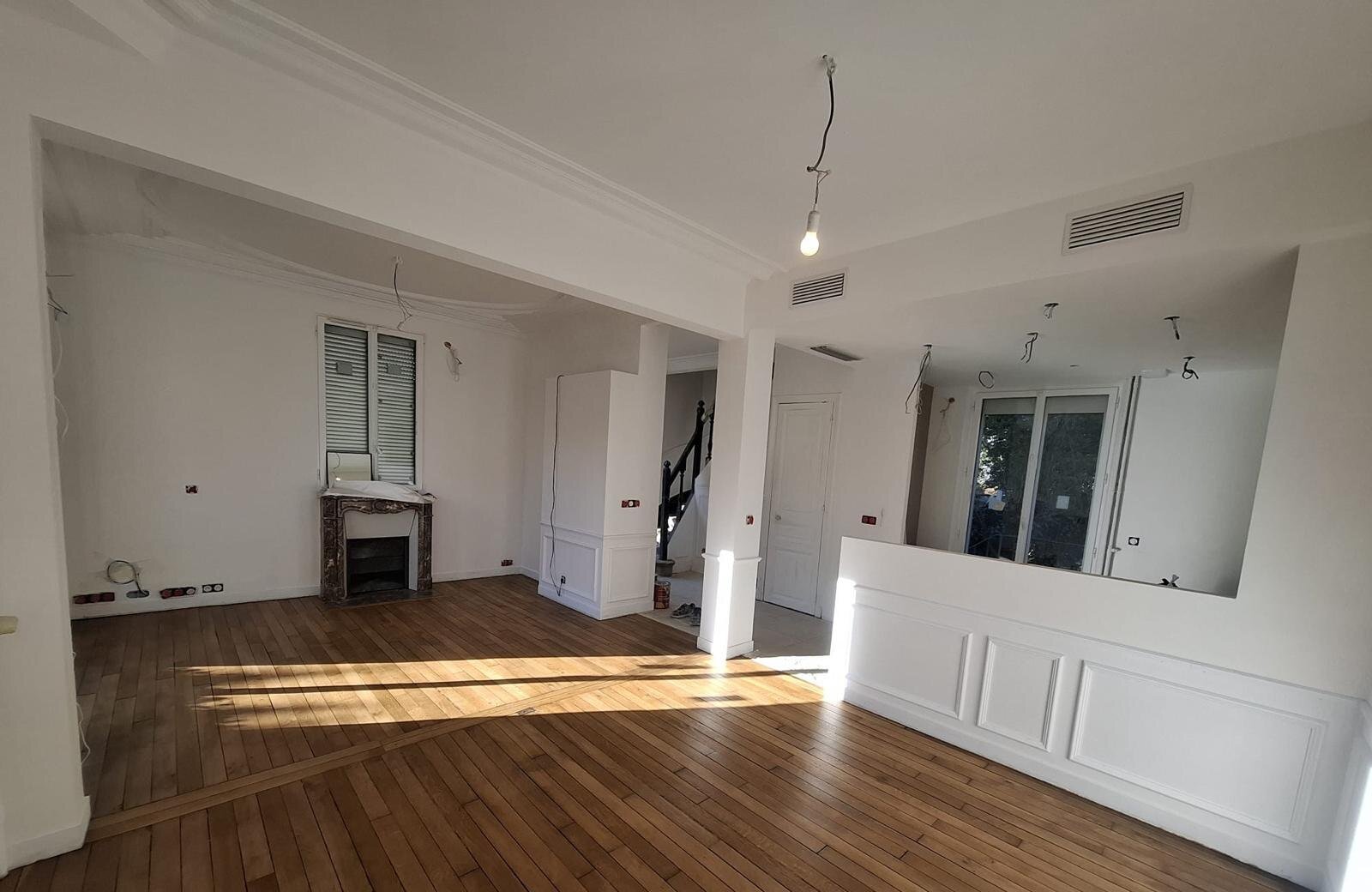 Séjour ouvert sur cuisine et escalier, parquet massif et cheminée en marbre